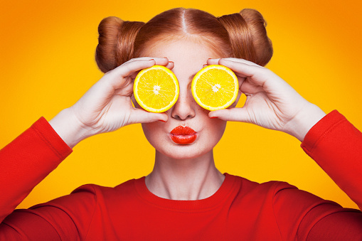 Young beautiful funny fashion model with lemon slice on orange background. ; comments for girls