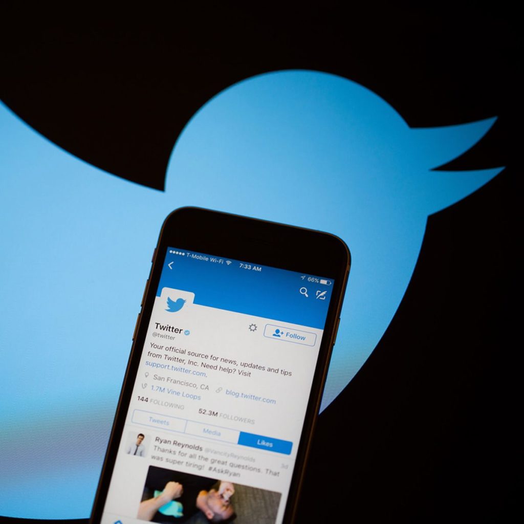Phone in Twitter logo background ; How to find your missing Twitter DMs