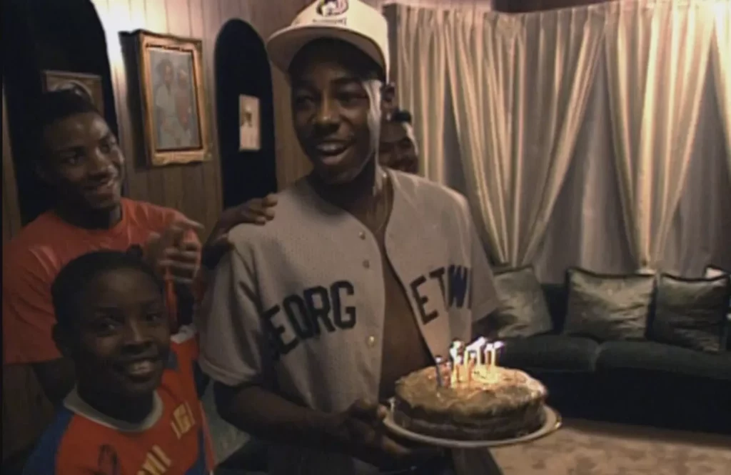 A boywith a birthday cake in hands with candles lighted on top of it; Where to watch Hoop Dreams